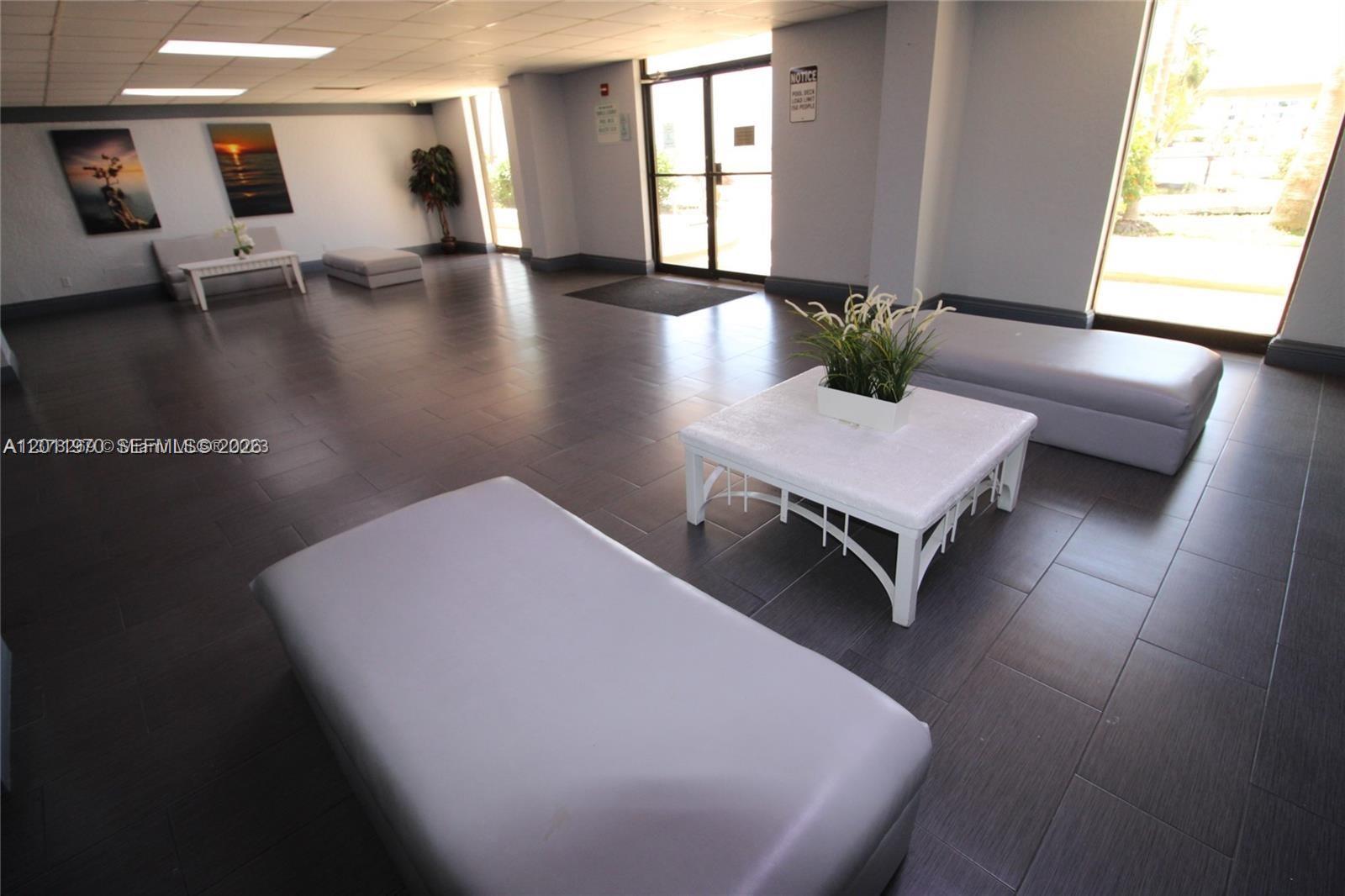 A spacious lobby features dark tile flooring, modern seating, and large glass entry doors — 13499 Biscayne Blvd # 404, North Miami FL 33181, NORTH MIAMI, FL