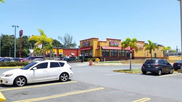 A Popeyes restaurant building sits in a parking lot with palm trees under a blue sky — PR 693 INT JOSE EFRON AVE, DORADO, PR