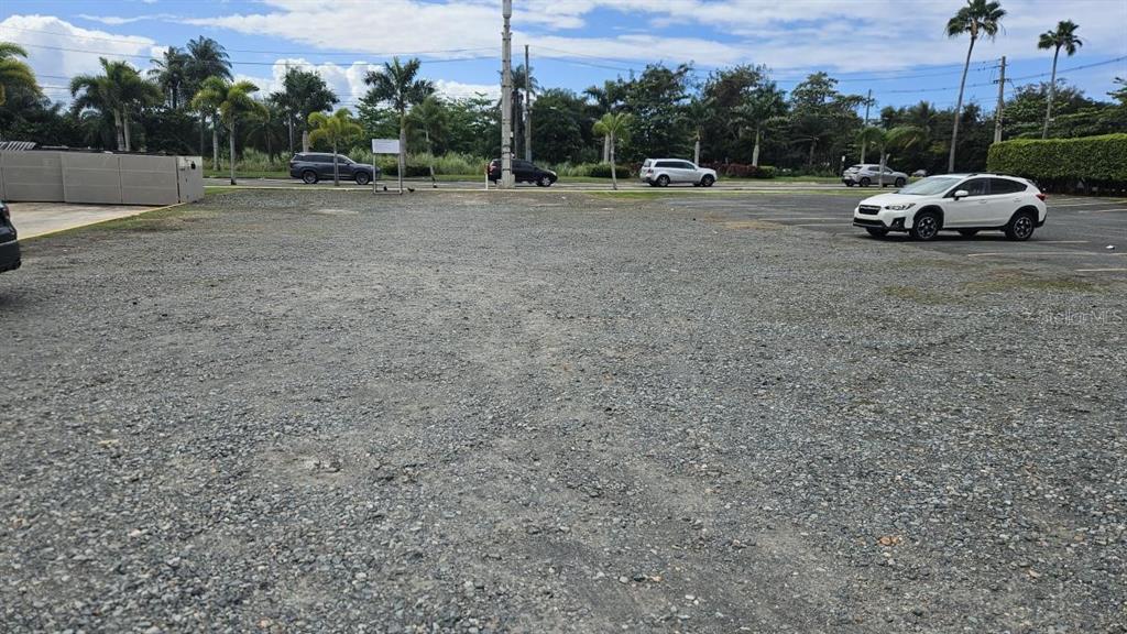 A gravel parking lot features several parked cars and palm trees under a blue sky — PR 693 INT JOSE EFRON AVE, DORADO, PR