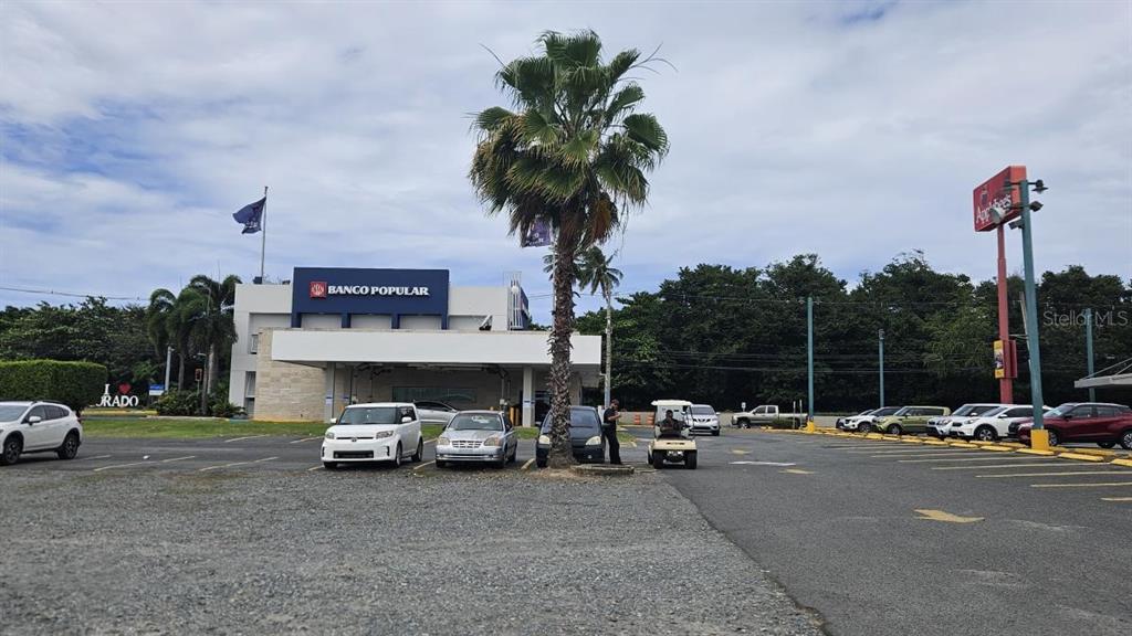 A Banco Popular branch building stands behind a parking lot with a palm tree — PR 693 INT JOSE EFRON AVE, DORADO, PR