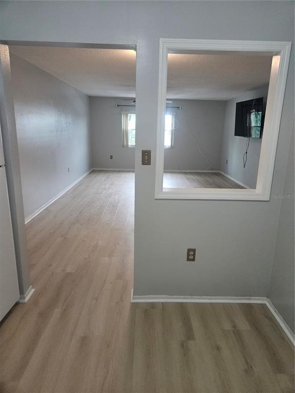 An interior view showing a living area with light wood-look flooring and a pass-through window — 1706 BELLEAIR FOREST DRIVE UNIT 310, CLEARWATER, FL