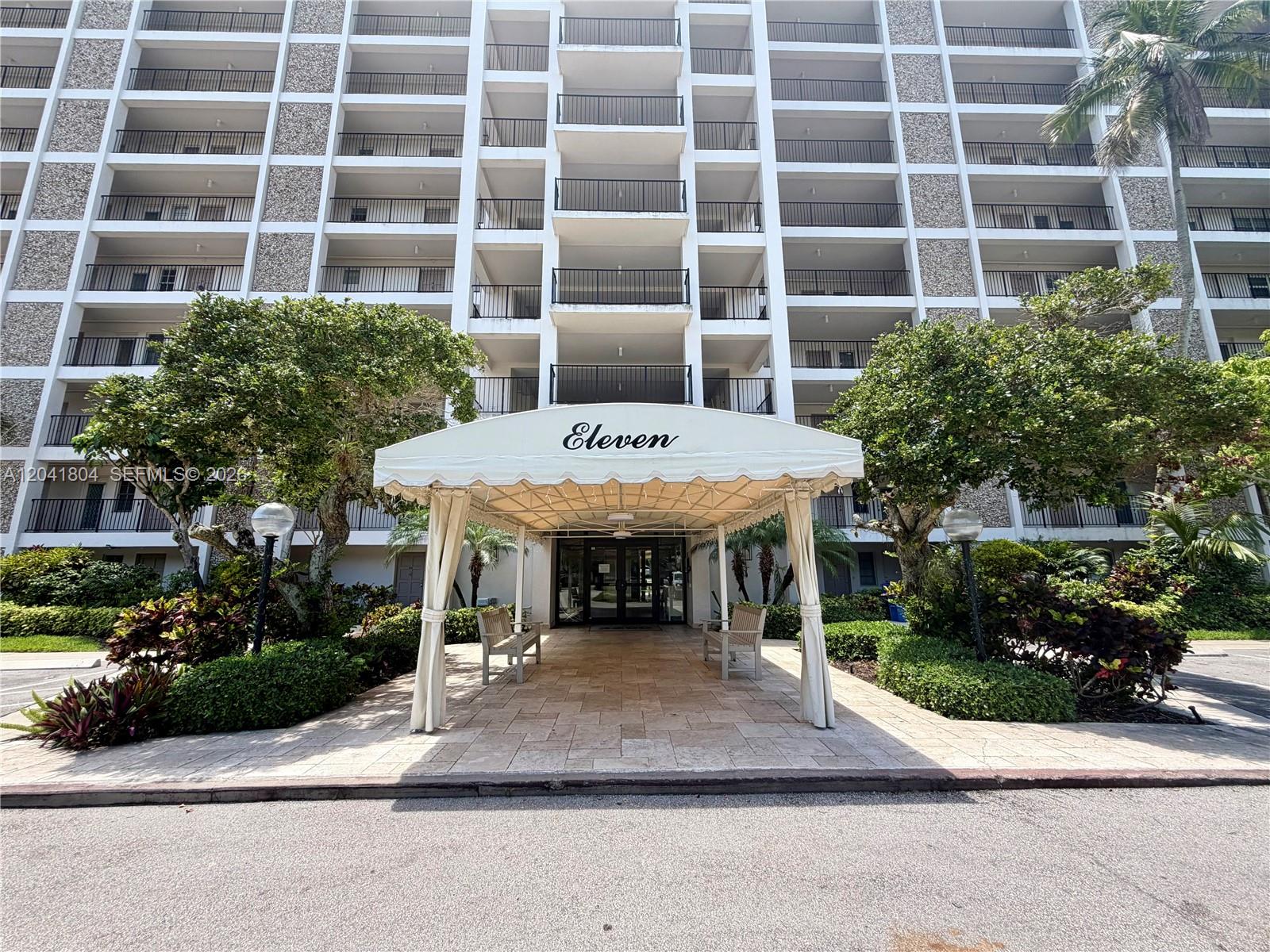 The exterior of a multi-story apartment building features a covered entrance with an Eleven sign — 3200 N Palm Aire Dr # 710, Pompano Beach FL 33069, POMPANO BEACH, FL