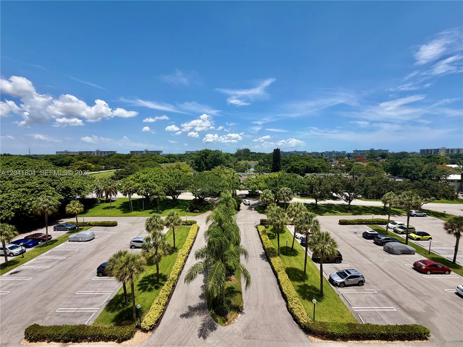 An elevated view shows a parking lot surrounded by palm trees and lush green landscaping — 3200 N Palm Aire Dr # 710, Pompano Beach FL 33069, POMPANO BEACH, FL