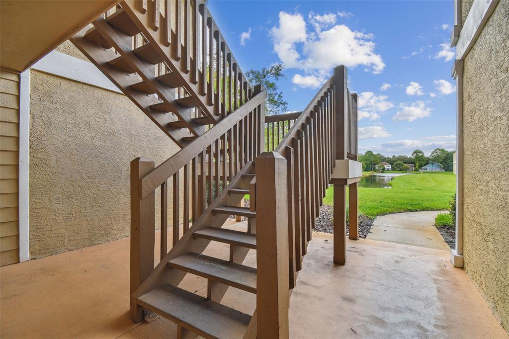 An exterior view of a wooden staircase leading to an upper level apartment balcony — 9481 HIGHLAND OAK DRIVE UNIT 1615, TAMPA, FL