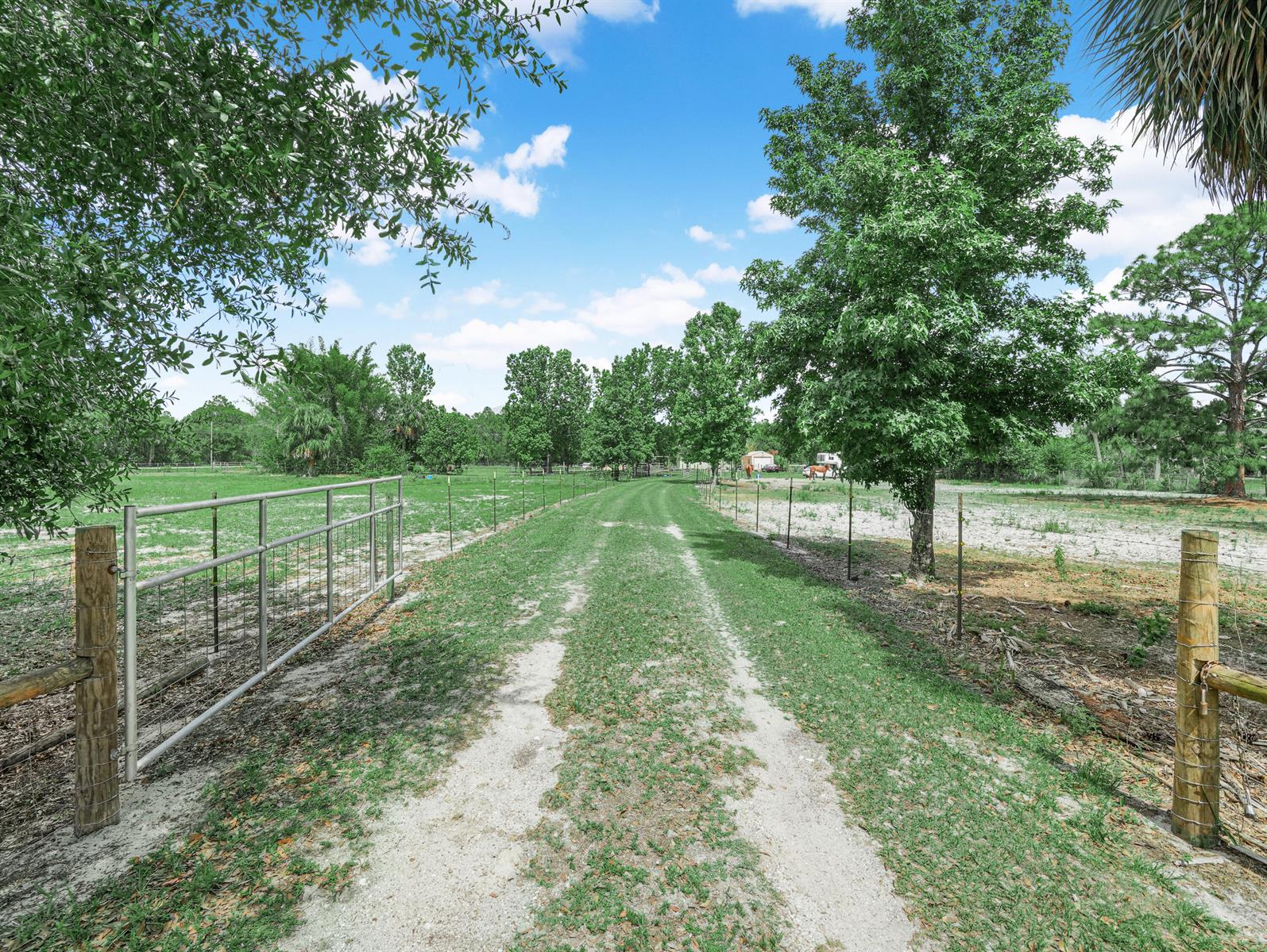 A dirt path leads through a metal gate into a fenced, grassy pasture with trees — 4002 Everhigh Acres Road, Clewiston FL 33440, CLEWISTON, FL
