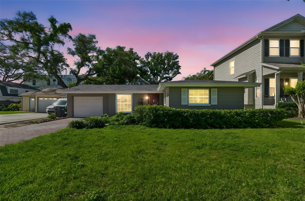 A single-story gray house with a garage and a large front lawn at sunset — 4906 W CLEVELAND STREET, TAMPA, FL