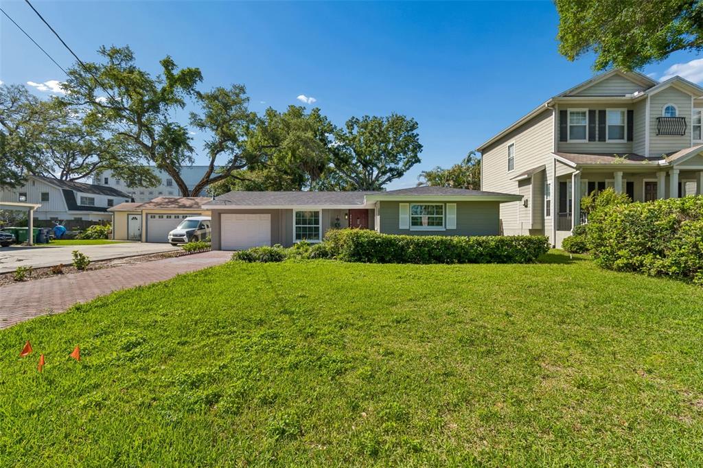 A single-story house with a gray exterior, a white garage, and a large front lawn — 4906 W CLEVELAND STREET, TAMPA, FL
