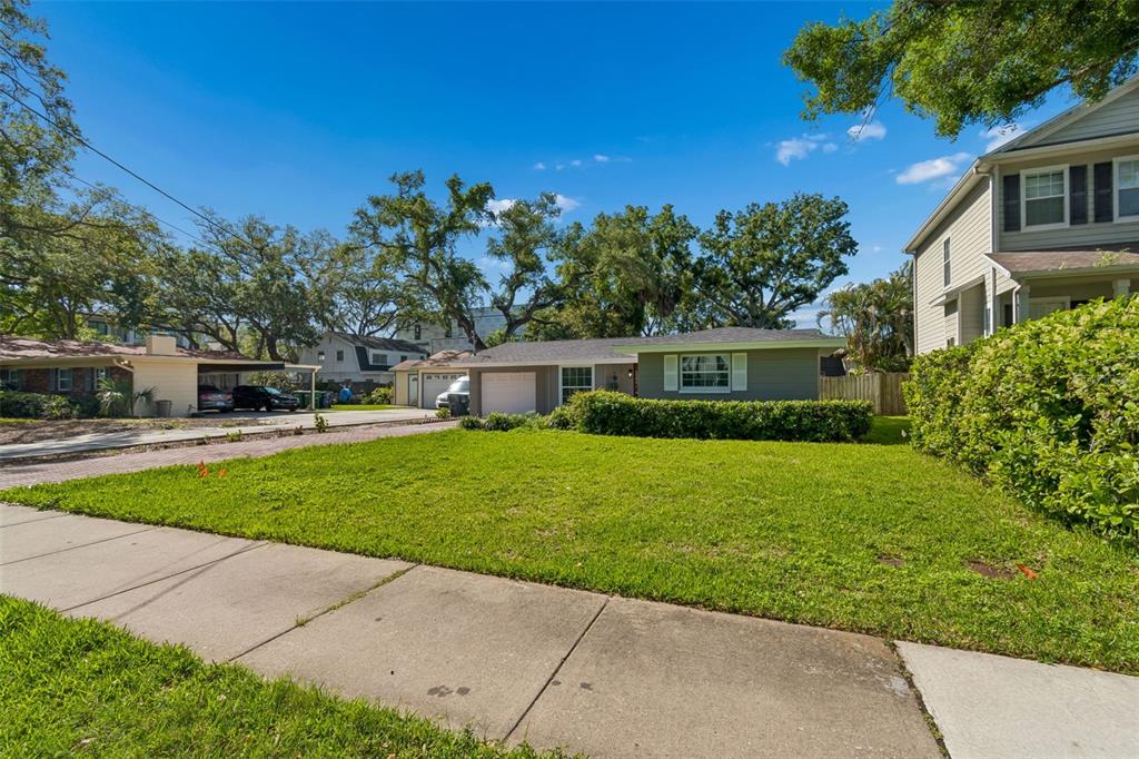 A single-story house with a green exterior, white trim, and a front lawn — 4906 W CLEVELAND STREET, TAMPA, FL