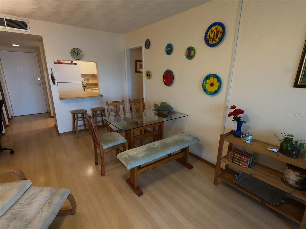 A dining area features a glass-top table with chairs and a bench on wood flooring — 19451 GULF BOULEVARD UNIT 604, INDIAN SHORES, FL