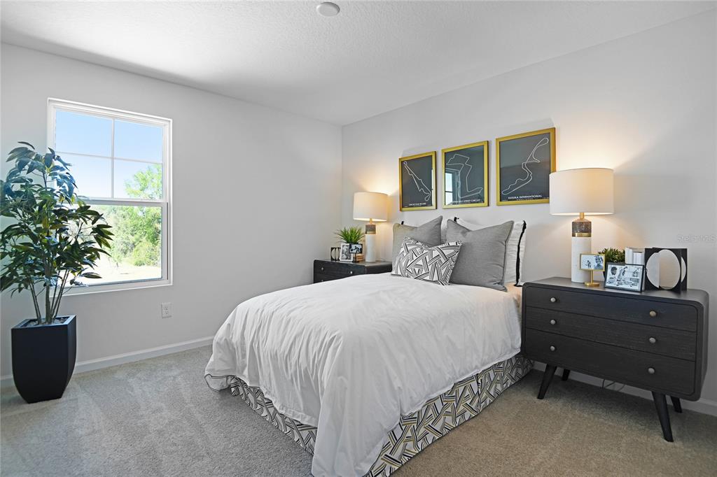 A bedroom features a bed with a patterned bed skirt, two nightstands, and framed wall art — 14530 BANKS COURT, PARRISH, FL
