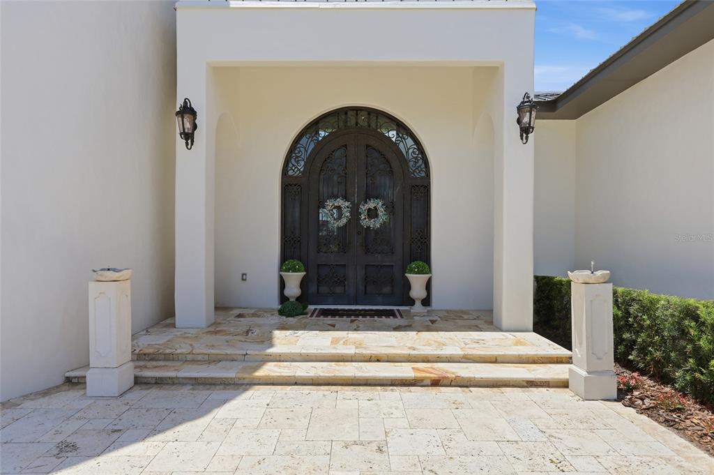 A stone-paved entryway features a double arched iron door flanked by two white pedestals — 12623 PARK AVENUE, WINDERMERE, FL