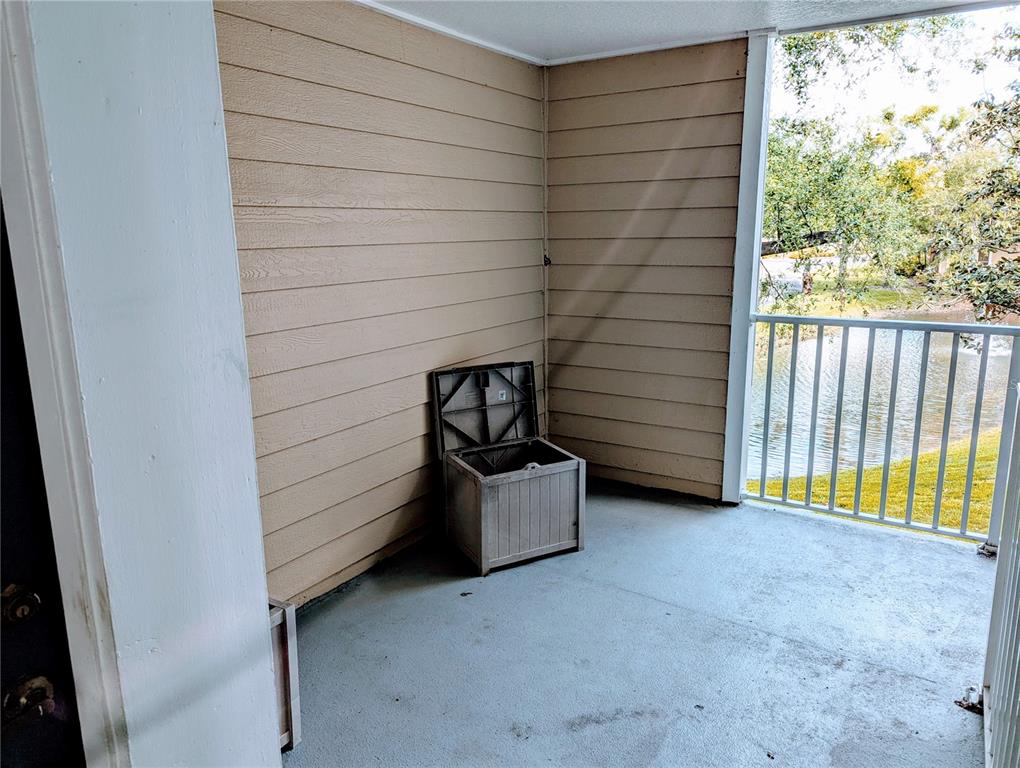 A balcony with tan horizontal siding, a concrete floor, a storage bin, and metal railings — 4211 CHATHAM OAK COURT UNIT 111, TAMPA, FL