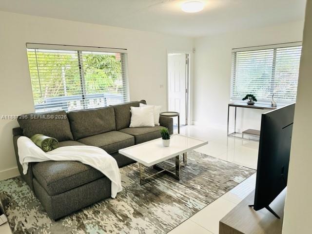 A living room features a gray sectional sofa, a white coffee table, and large windows — 1030 NE 80th St # 4, Miami FL 33138, MIAMI, FL