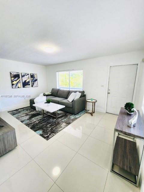 A living room with a gray sectional sofa, a white coffee table, and tile flooring — 1030 NE 80th St # 4, Miami FL 33138, MIAMI, FL