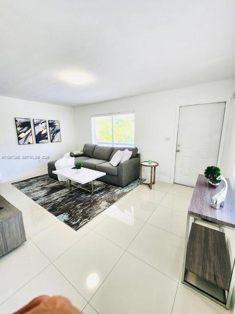 A living room features a gray sectional sofa, a coffee table, and light tile flooring — 1030 NE 80th St # 4, Miami FL 33138, MIAMI, FL