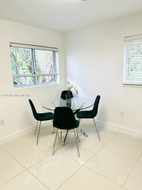 A dining area features a glass-topped table, four green velvet chairs, and white tile flooring — 1030 NE 80th St # 4, Miami FL 33138, MIAMI, FL