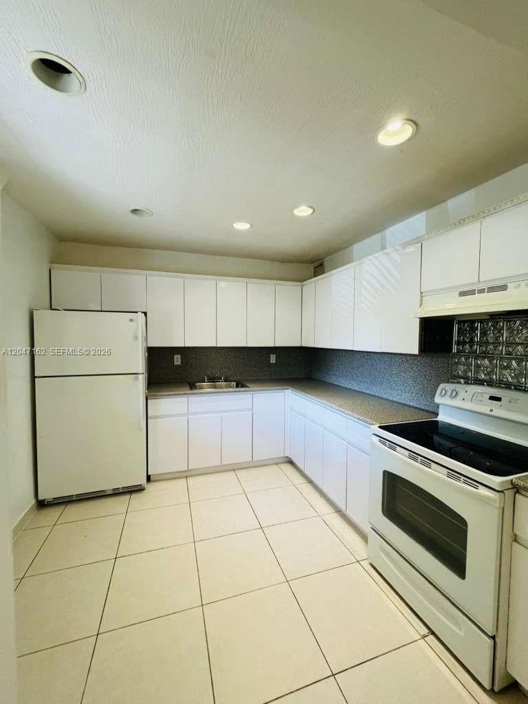 A kitchen features white cabinets, white appliances, a grey countertop, and light-colored tile flooring — 724 NE 4th St # 9, Hallandale Beach FL 33009, HALLANDALE BEACH, FL