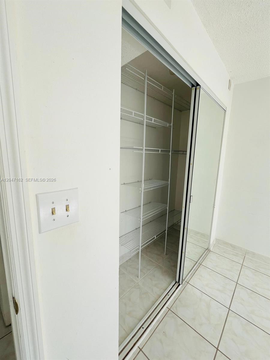 A closet with wire shelving and mirrored sliding doors is adjacent to a light switch — 724 NE 4th St # 9, Hallandale Beach FL 33009, HALLANDALE BEACH, FL