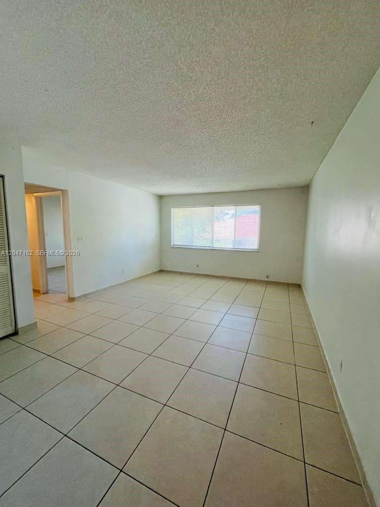 An empty room features white walls, a textured ceiling, and light-colored tiled flooring — 724 NE 4th St # 9, Hallandale Beach FL 33009, HALLANDALE BEACH, FL