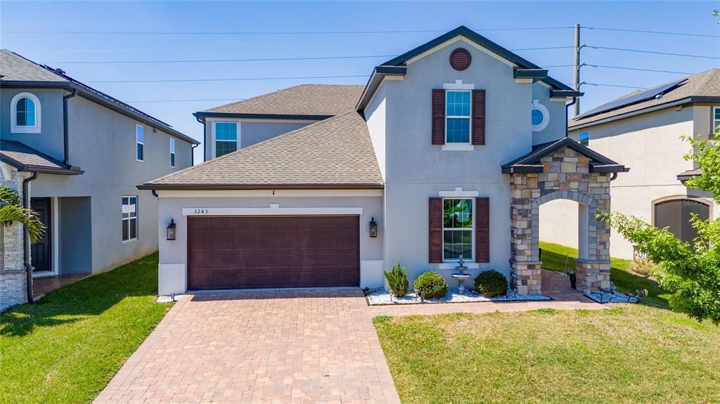 A two-story suburban house with a stone-accented entryway, brown garage door, and paved driveway — 3243 PALATKA STREET, ORLANDO, FL