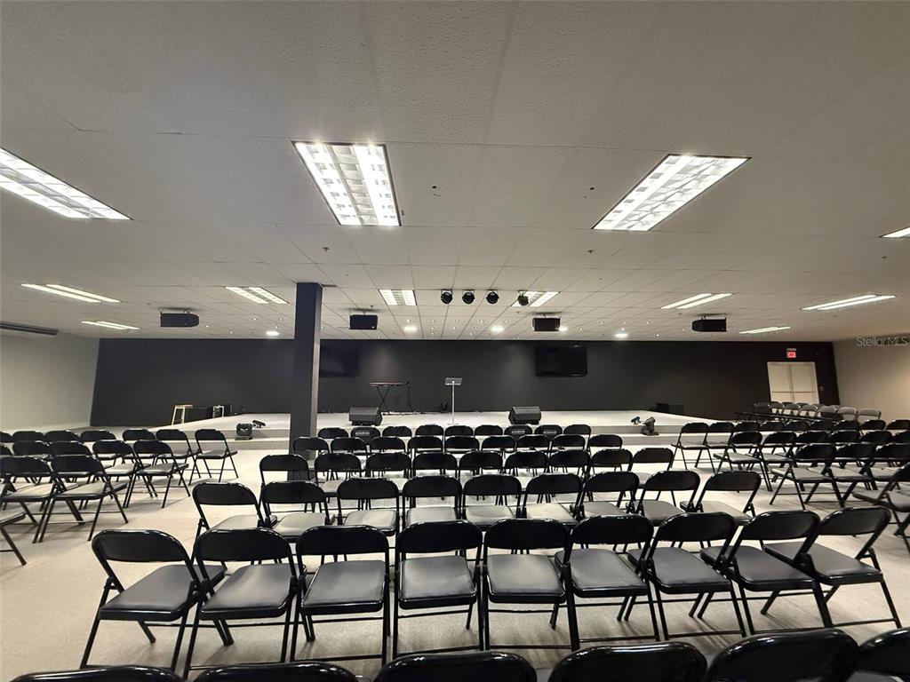 A large room with rows of black folding chairs facing a raised stage area — 272 CALLE 272 BLOQ. L B 12, URB. COUNTRY CLUB, CAROLINA, PR