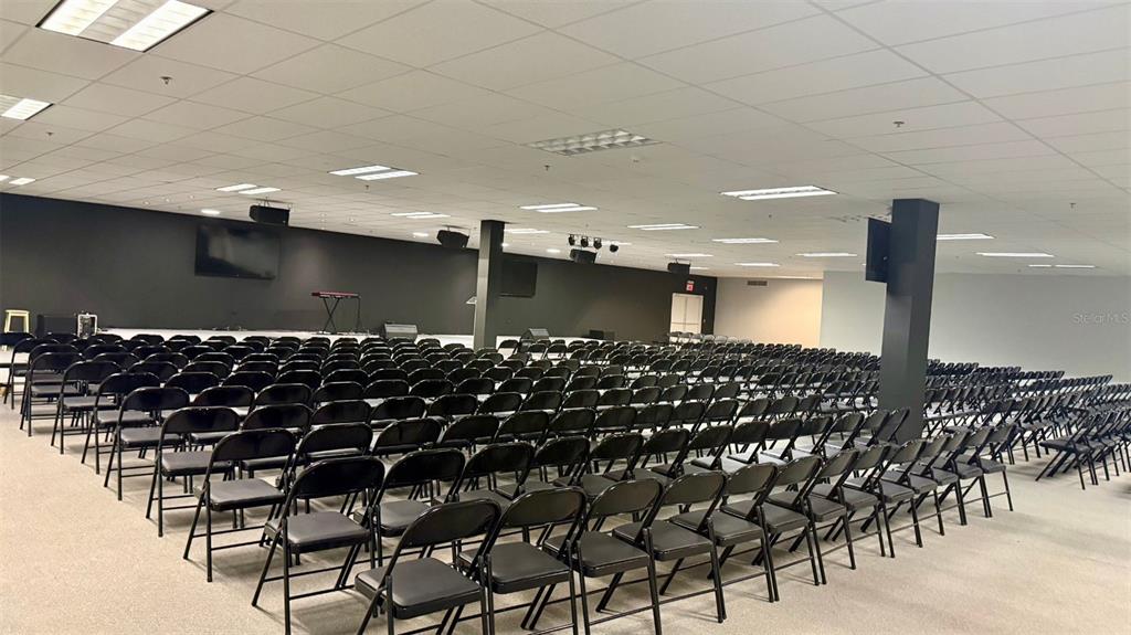 A large, open room features rows of black folding chairs facing a dark accent wall — 272 CALLE 272 BLOQ. L B 12, URB. COUNTRY CLUB, CAROLINA, PR