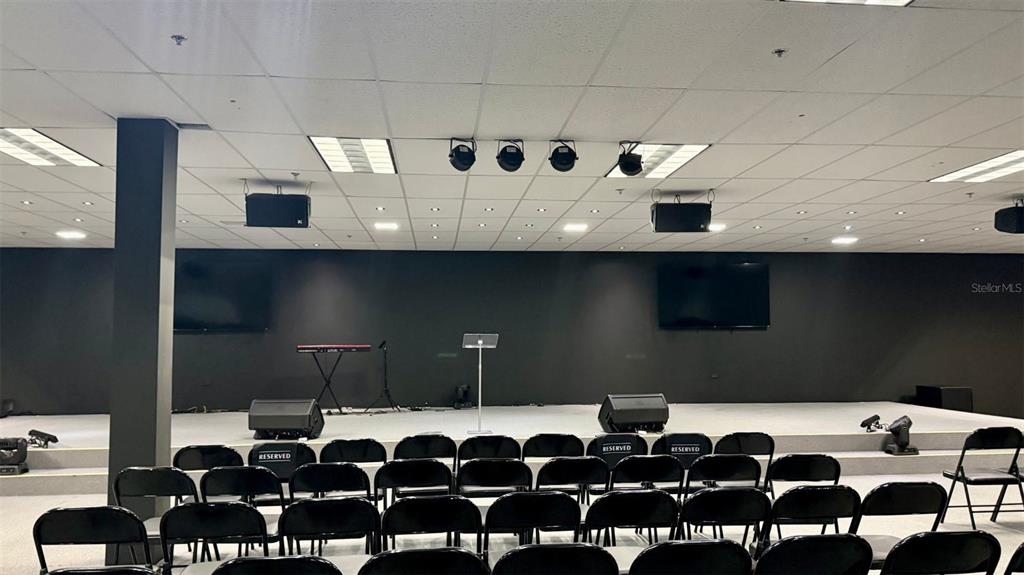 A stage with a keyboard and podium faces rows of black chairs in a room — 272 CALLE 272 BLOQ. L B 12, URB. COUNTRY CLUB, CAROLINA, PR