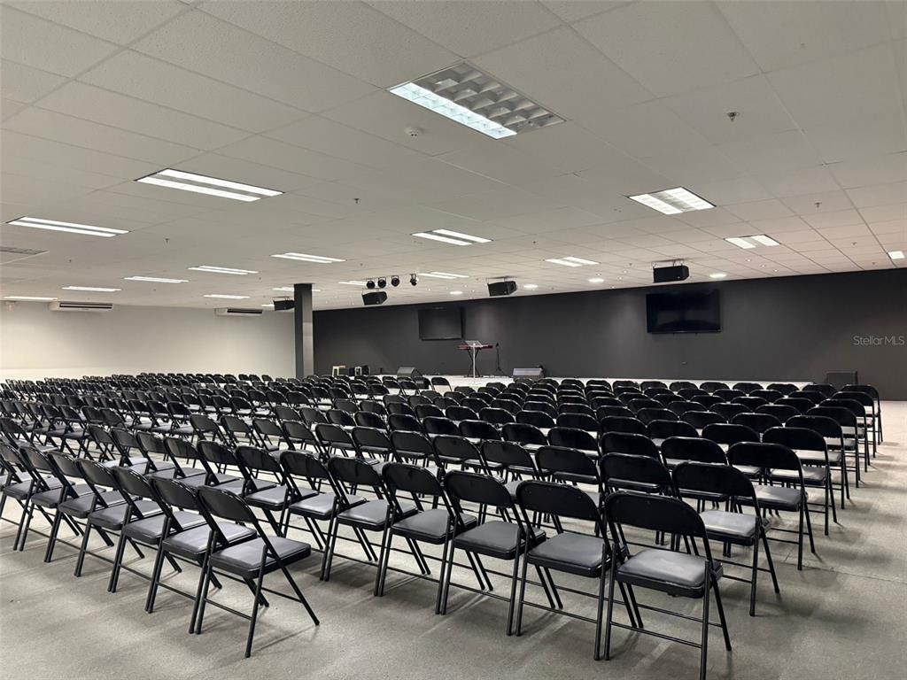 A large, open room features rows of black folding chairs facing a dark stage — 272 CALLE 272 BLOQ. L B 12, URB. COUNTRY CLUB, CAROLINA, PR