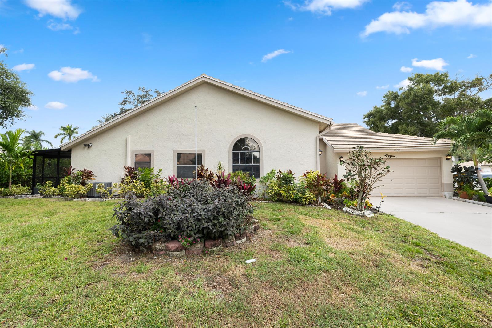 A single-story house with a beige stucco exterior, a garage, and a landscaped front yard — 10933 Stafford Circle S, Boynton Beach FL 33436, BOYNTON BEACH, FL