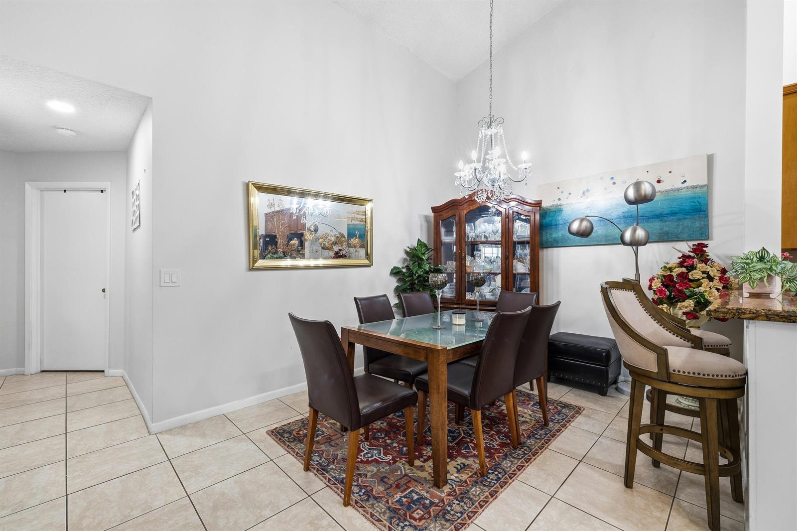 A dining area features a glass-top table, dark chairs, a china cabinet, and a chandelier — 10933 Stafford Circle S, Boynton Beach FL 33436, BOYNTON BEACH, FL