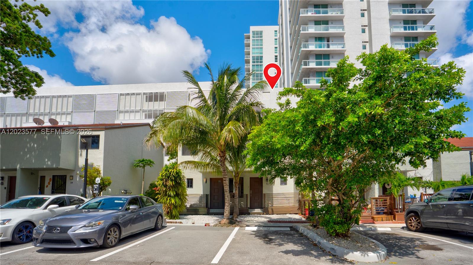 An exterior view shows a multi-story residential building with parking spaces and palm trees — 1901 NW S River Dr # 12B, Miami FL 33125, MIAMI, FL