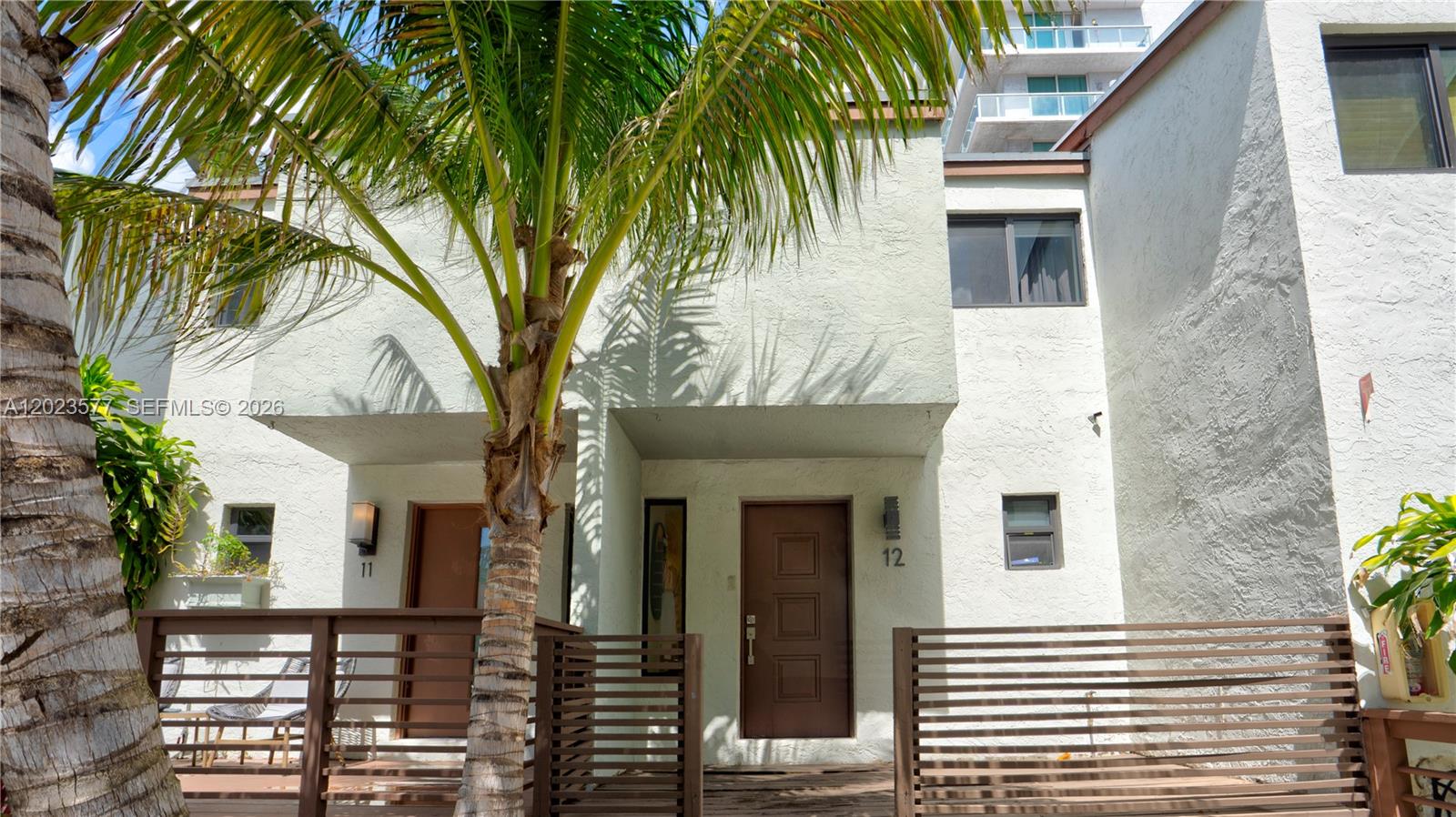 Exterior view of two adjacent townhome units with brown doors and wooden privacy fences — 1901 NW S River Dr # 12B, Miami FL 33125, MIAMI, FL