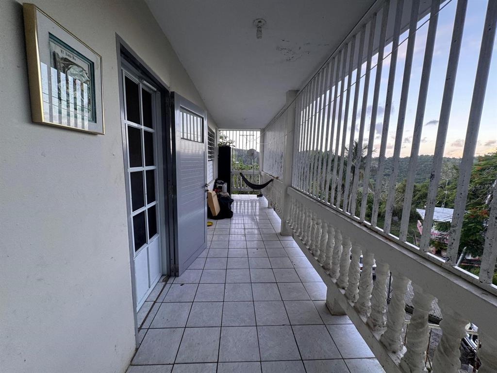 A tiled balcony features a white metal railing, a glass door, and a hammock — 62.2 KM. CARR#1 BO PEDRO DAVILA, CAYEY, PR