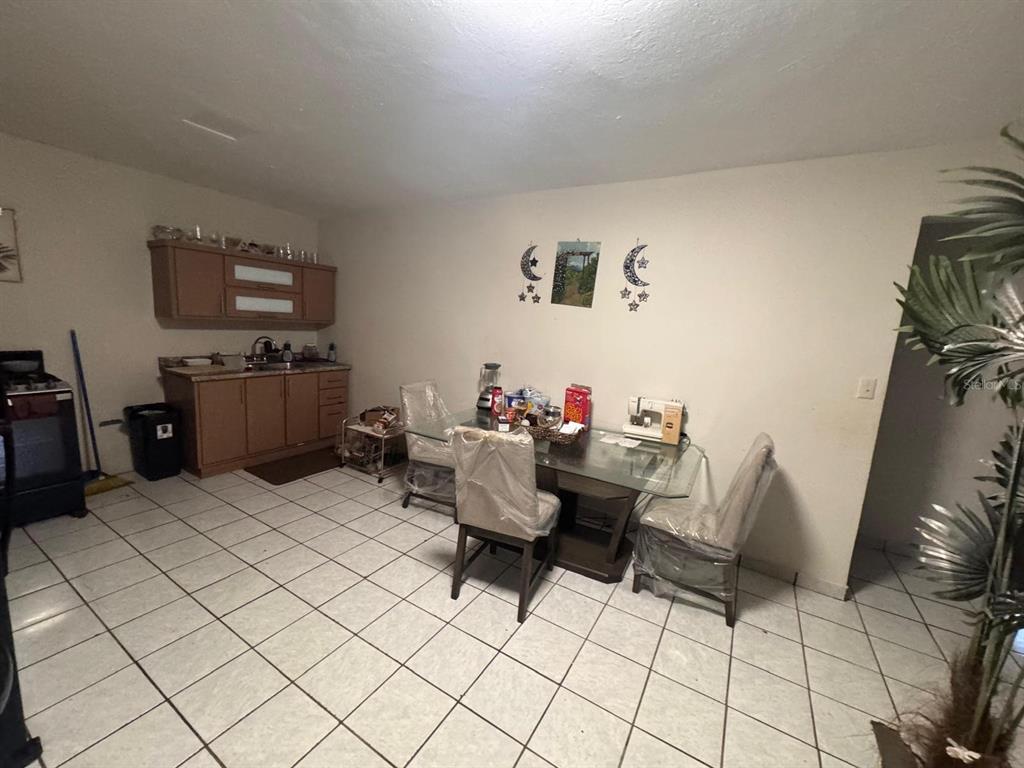 A kitchen and dining area with tile floors, wooden cabinets, and a glass-topped table — 62.2 KM. CARR#1 BO PEDRO DAVILA, CAYEY, PR