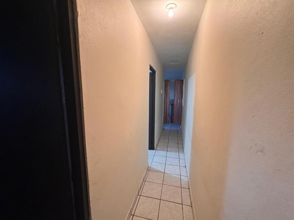 A narrow hallway features light-colored walls, a tiled floor, and a single ceiling light fixture — 62.2 KM. CARR#1 BO PEDRO DAVILA, CAYEY, PR