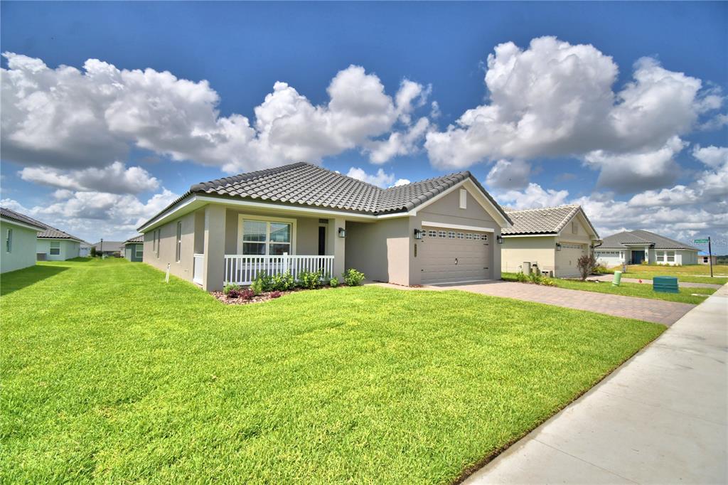 A single-story suburban house with a tan exterior, tiled roof, and a paved driveway — 4663 GRANDVIEW GLEN DRIVE, AUBURNDALE, FL