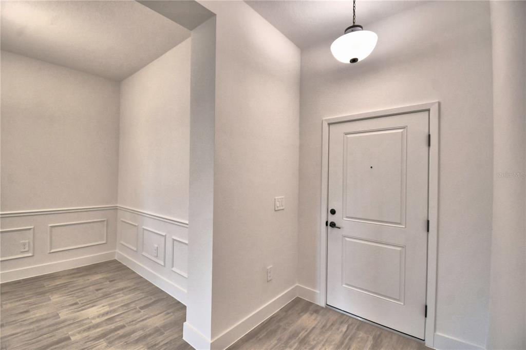 An entryway features white walls, wainscoting, a light fixture, and wood-look flooring — 4663 GRANDVIEW GLEN DRIVE, AUBURNDALE, FL