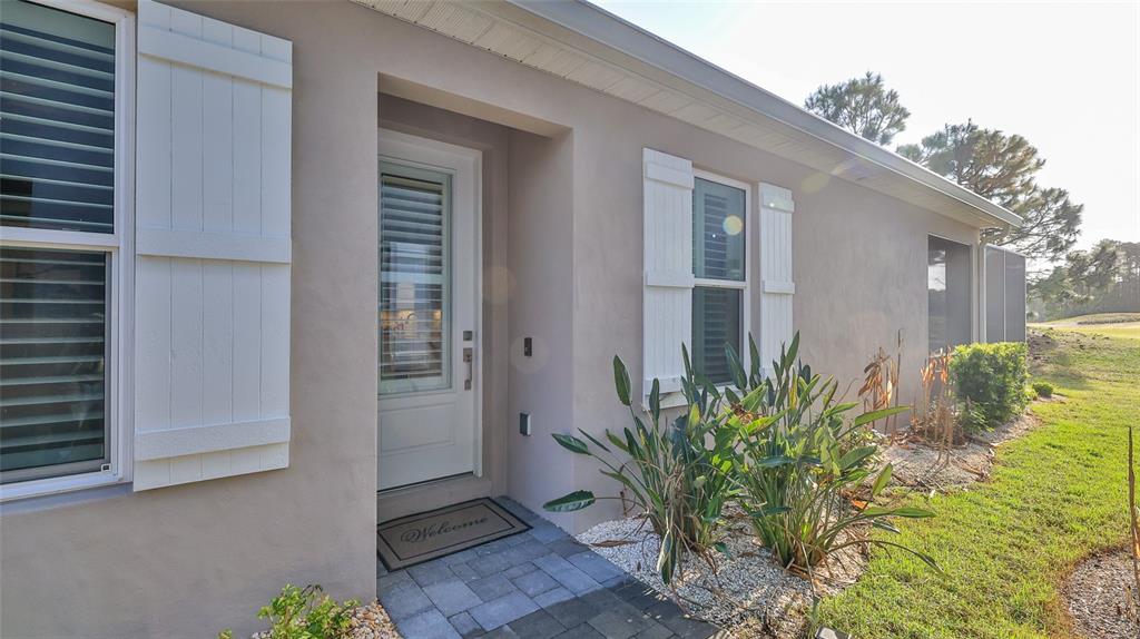 The exterior of a house features a white front door, shutters, and a paved walkway — 3058 ISLES WAY, NEW SMYRNA BEACH, FL