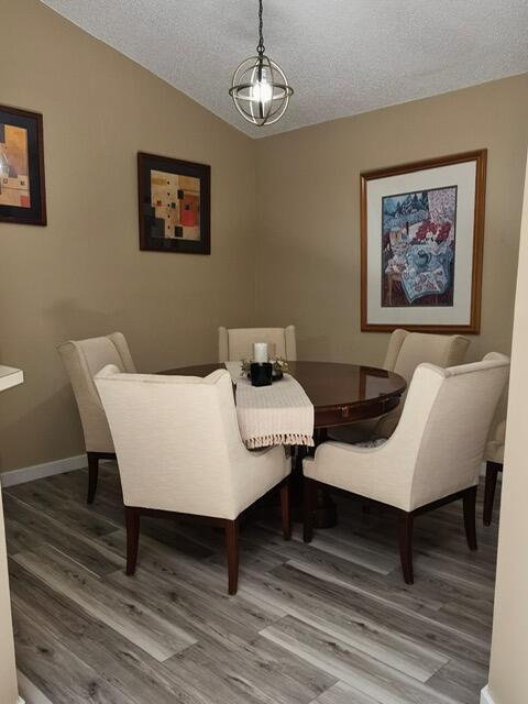 A dining room features a round wooden table, four upholstered chairs, and wood-look flooring — 6531 SE Federal Highway # F211, Stuart FL 34997, STUART, FL
