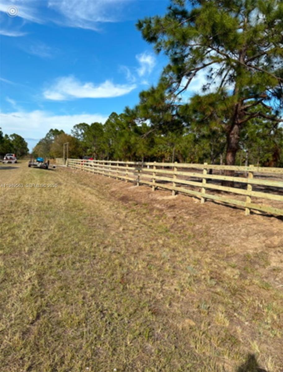 A wooden split-rail fence runs along a grassy field bordered by pine trees — 845 S WILLOW ST, Clewiston FL 33440, CLEWISTON, FL