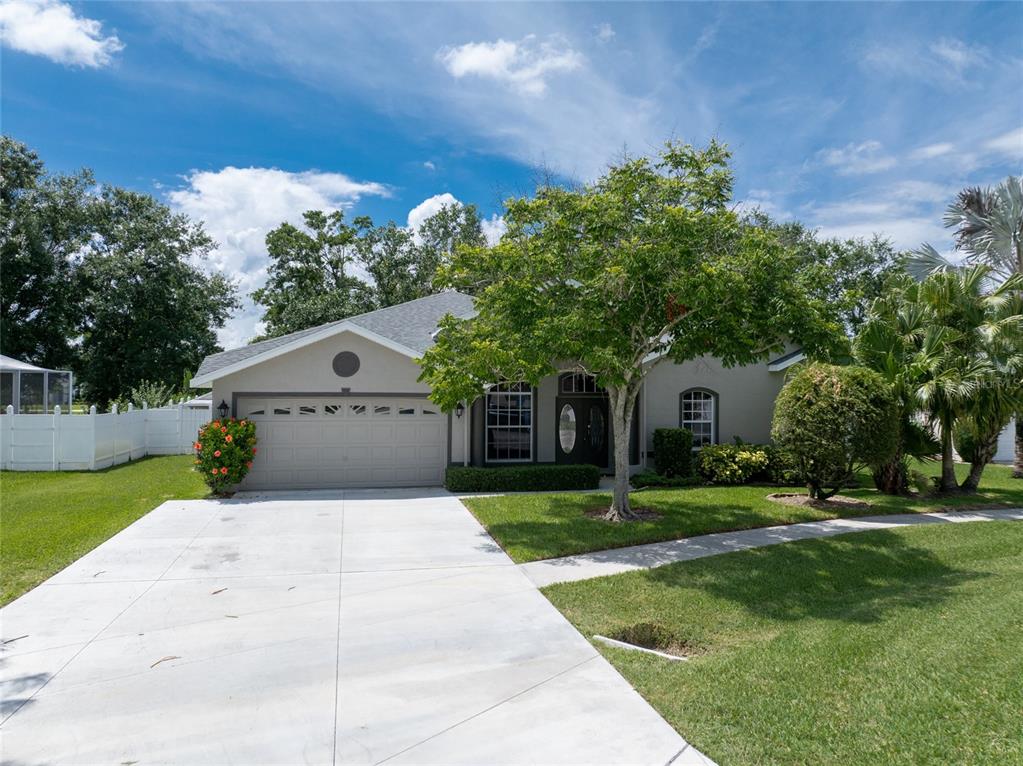 A single-story house with a two-car garage, a concrete driveway, and a large front tree — 21629 SILVER BAY PLACE, LAND O LAKES, FL