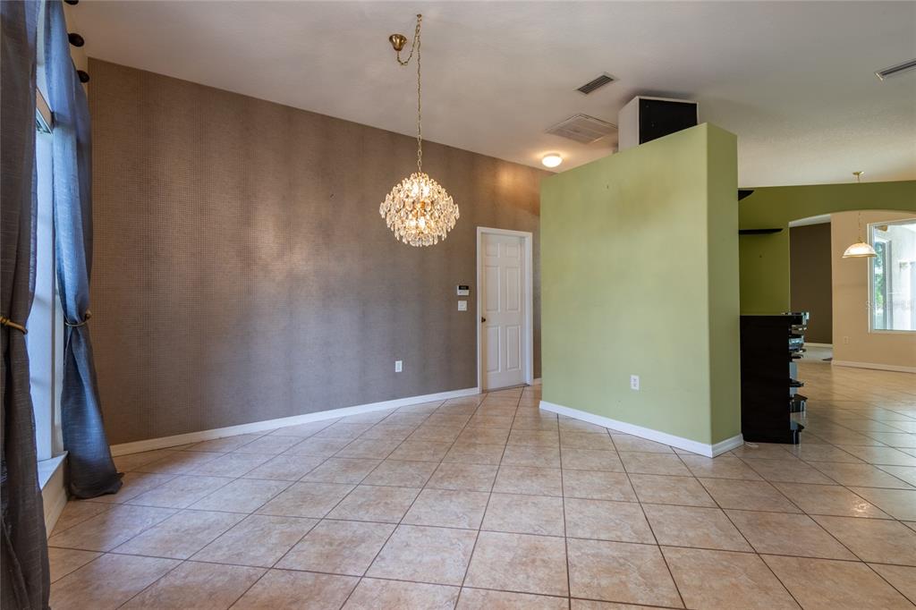 An interior room features a textured brown wall, a green partition, and a crystal chandelier — 21629 SILVER BAY PLACE, LAND O LAKES, FL