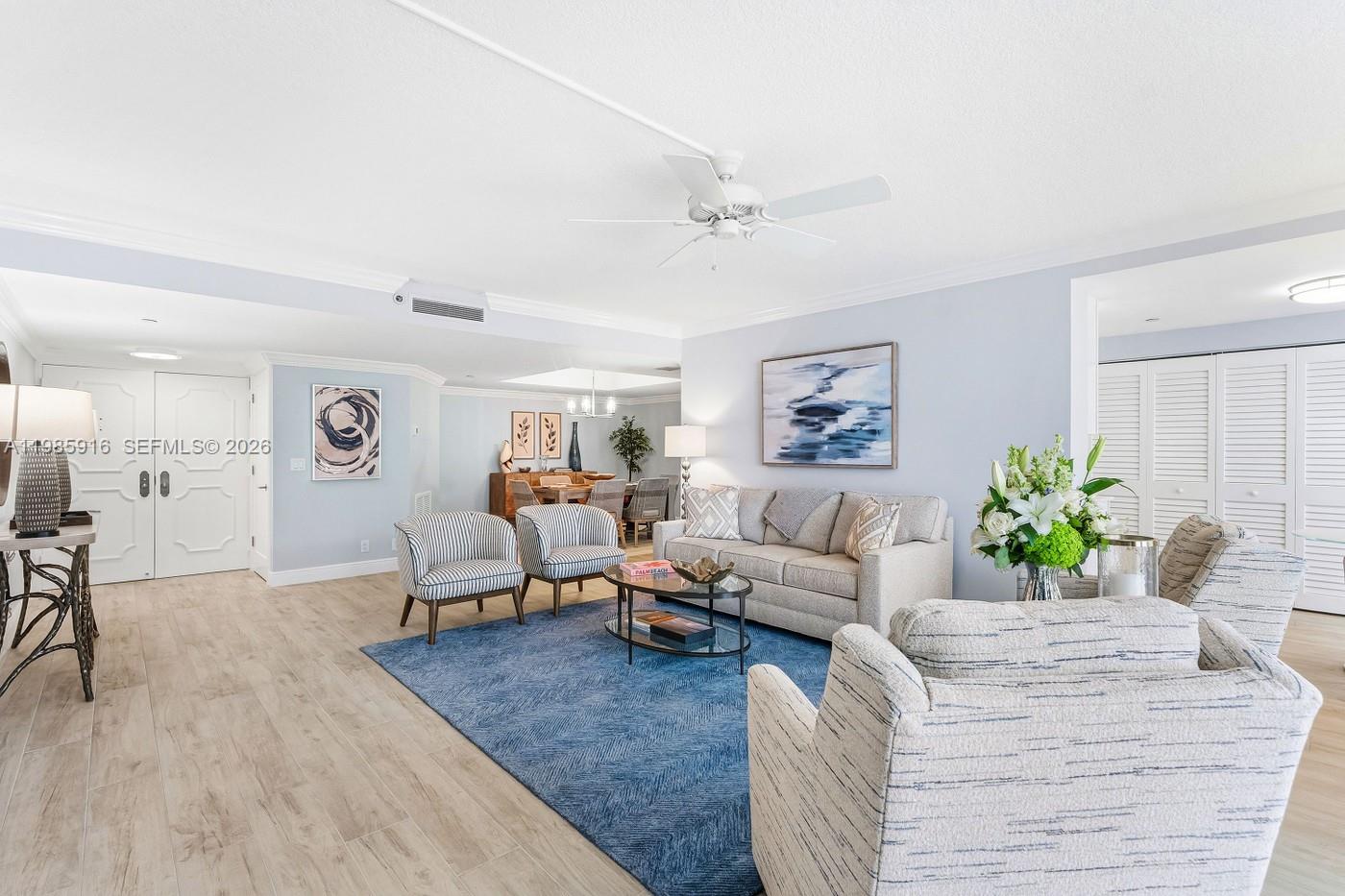 A living room features light wood flooring, a blue area rug, and neutral-toned furniture — 500 Ocean Dr # 12A, Juno Beach FL 33408, JUNO BEACH, FL