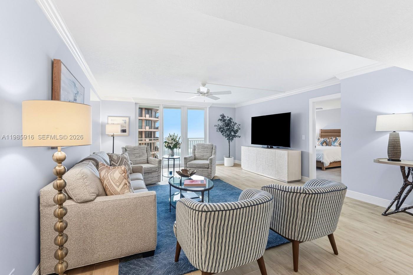 A living room features a blue rug, a sofa, striped armchairs, and a television console — 500 Ocean Dr # 12A, Juno Beach FL 33408, JUNO BEACH, FL