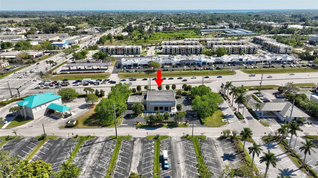 An aerial view shows a commercial building with a parking lot and surrounding road infrastructure — 3250 SE FEDERAL HIGHWAY, STUART, FL