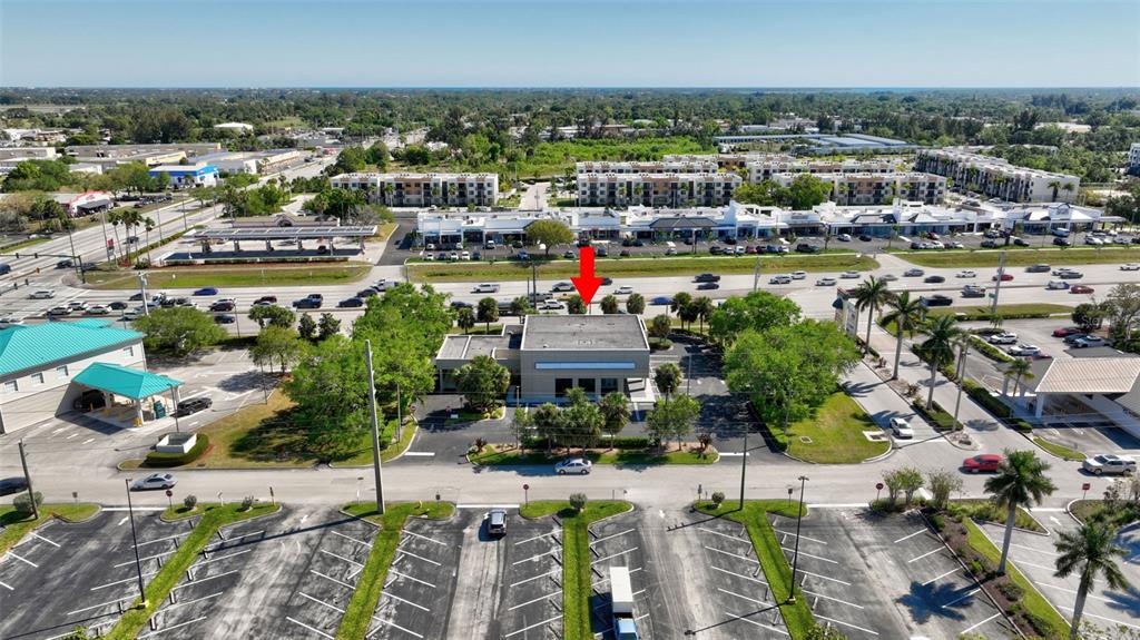 An aerial view shows a commercial building with a flat roof surrounded by parking lots — 3250 SE FEDERAL HIGHWAY, STUART, FL