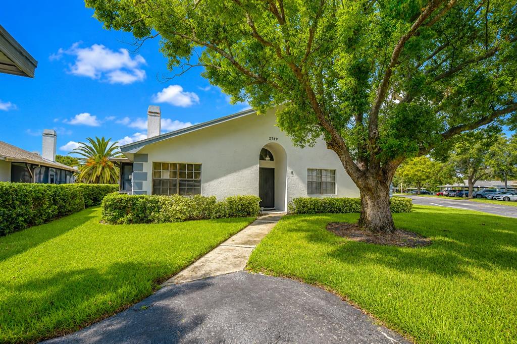 A single-story white house with a front walkway, a large tree, and a green lawn — 2749 COUNTRYSIDE BOULEVARD UNIT 8, CLEARWATER, FL