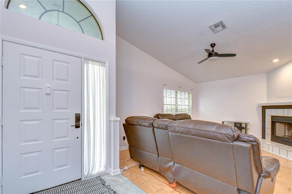 A living room features a brown leather sofa, a fireplace, and a white front door — 2749 COUNTRYSIDE BOULEVARD UNIT 8, CLEARWATER, FL