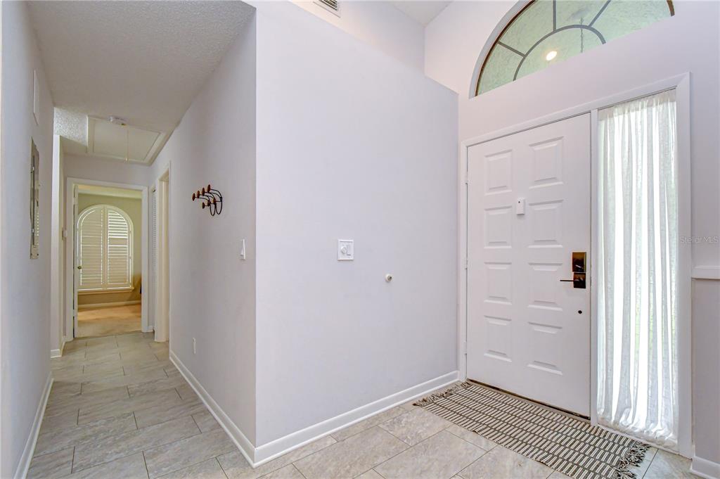 An entryway features a white front door with a sidelight, tile flooring, and arched window — 2749 COUNTRYSIDE BOULEVARD UNIT 8, CLEARWATER, FL