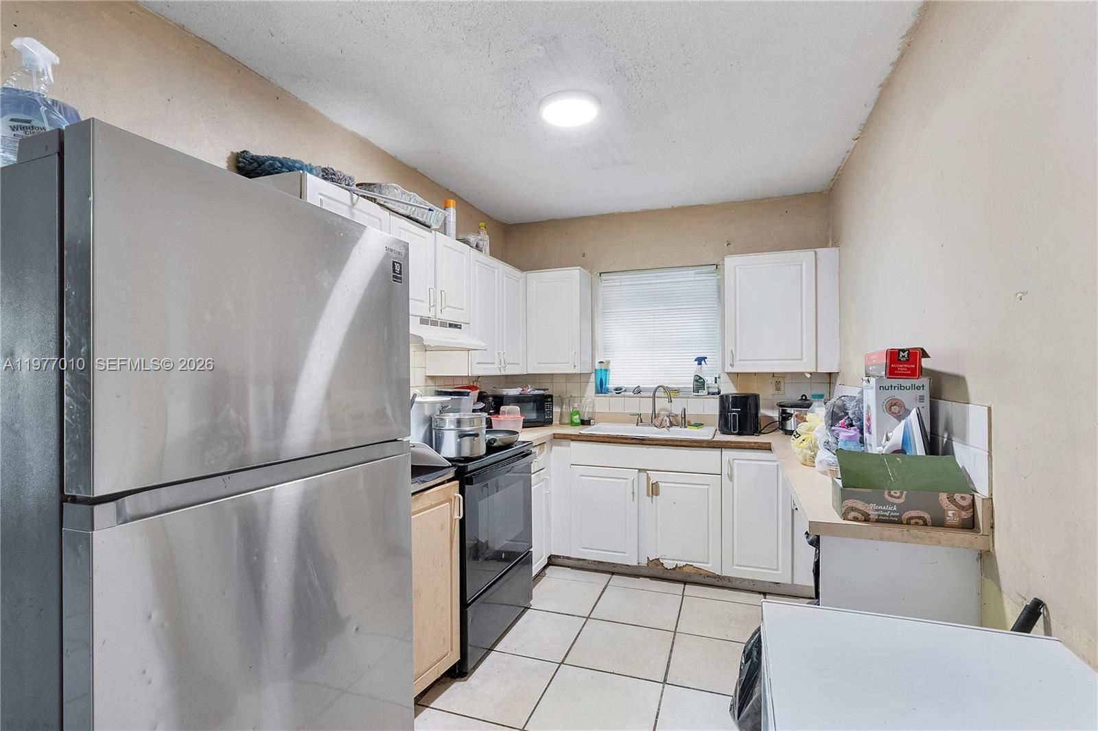 A small kitchen features white cabinets, stainless steel appliances, and light-colored floor tiles — 800 NW 33rd Ave, Lauderhill FL 33311, LAUDERHILL, FL